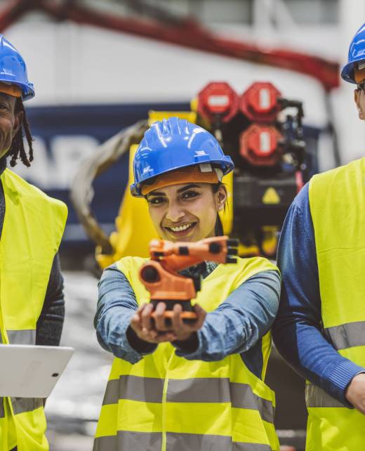 Diverse team of engineers smiling and holding a robotic arm prototype in an industrial facility. Diverse team of engineers smiling and holding a robotic arm prototype in an industrial facility.